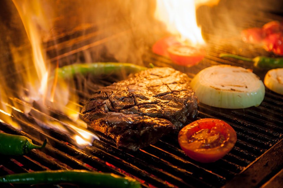 steak and vegetables on flaming grill