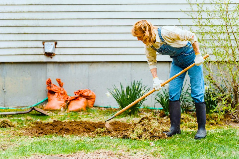 woman doing backyard spring cleaning work