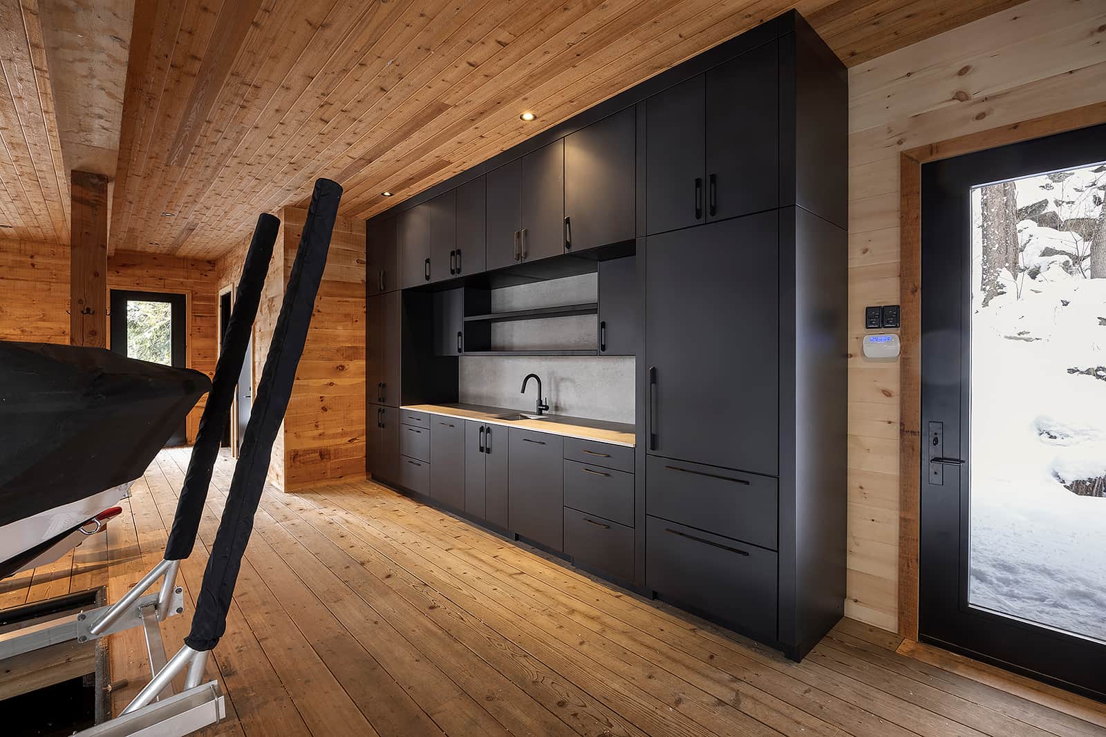 Floor-to-ceiling Alumina marine-grade aluminum cabinetry installed inside a Muskoka boathouse in matte black finish