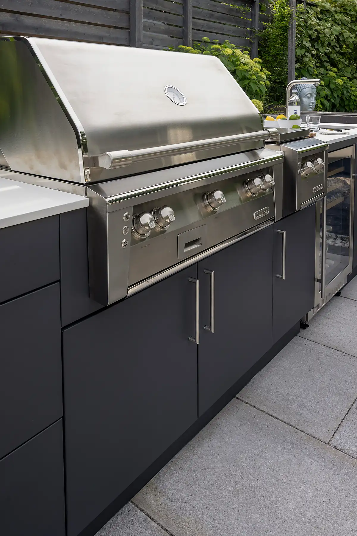 Modern covered terrace outdoor kitchen featuring flush limestone cabinetry wine bottle and glasses