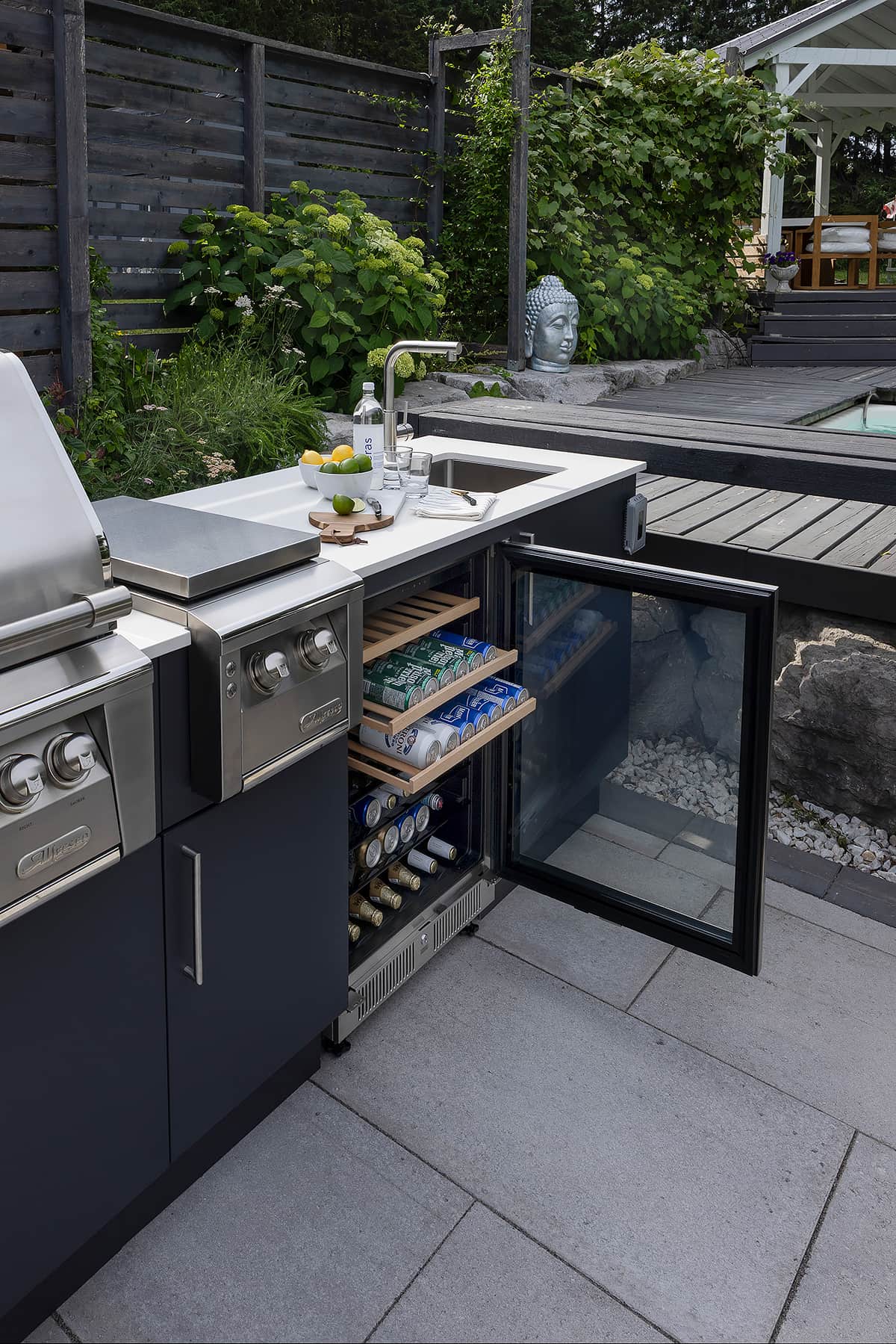 Modern covered terrace outdoor kitchen featuring flush limestone cabinetry wine bottle and glasses