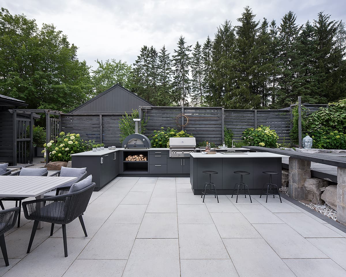Covered stone terrace outdoor kitchen with built in charcoal grill and flush Alumina cabinets
