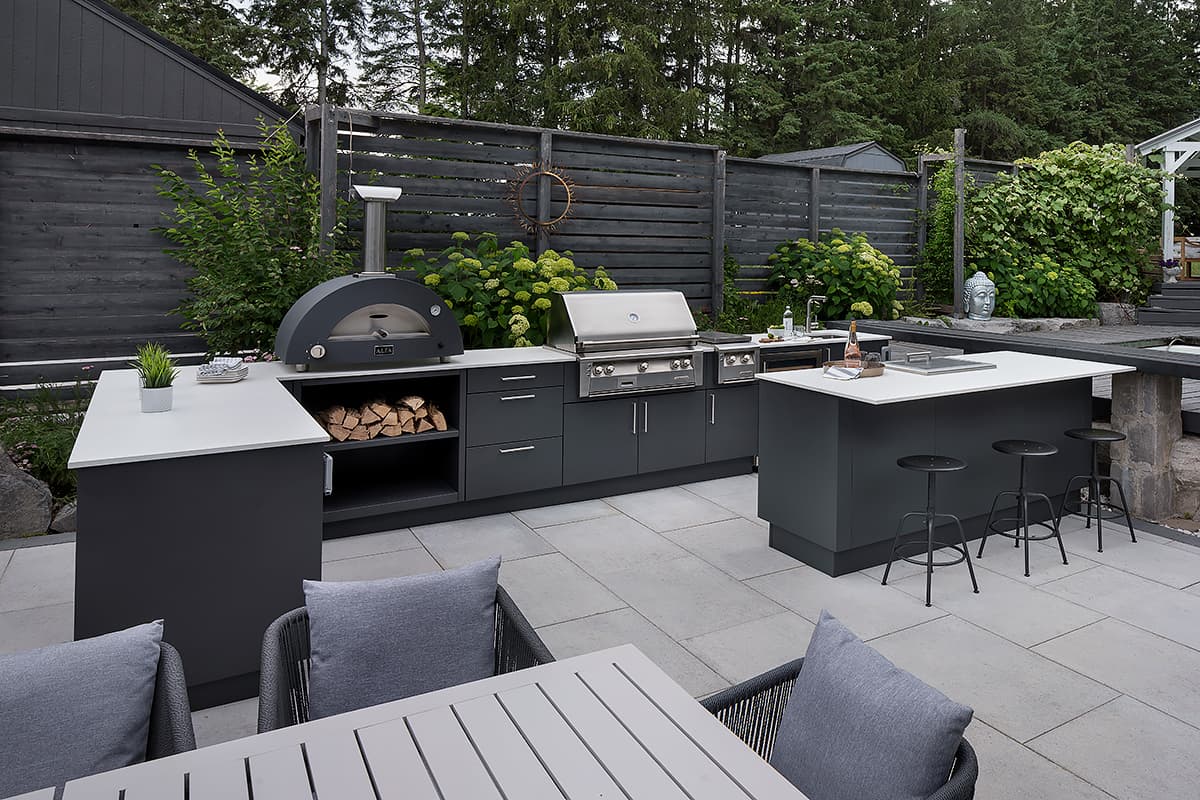 Modern two tier outdoor kitchen and covered stone patio on a manicured lawn