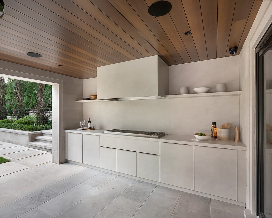Covered stone terrace outdoor kitchen with built in charcoal grill and flush Alumina cabinets