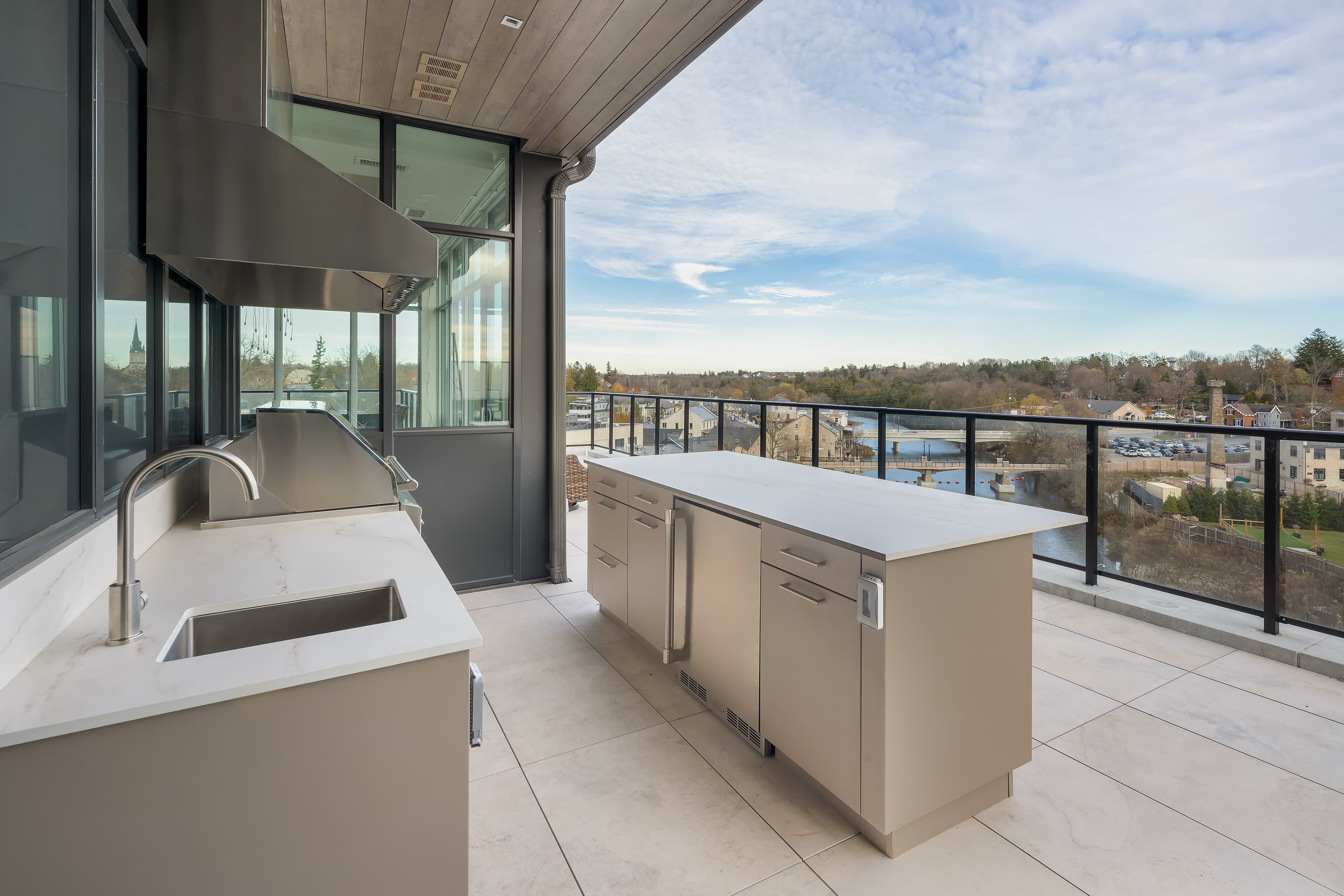 penthouse outdoor kitchen with large island, sink, fridge, range hood and river views