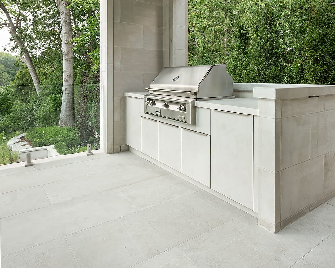 Modern outdoor kitchen with built in Alfresco grill and Alumina cabinetry on a covered terrace