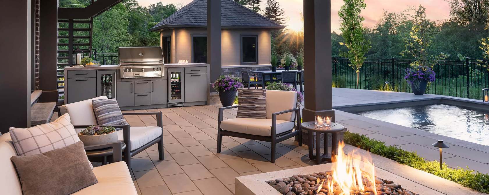 outdoor kitchen including grill, bar fridge, fire pit, pool in a backyard north of Toronto near sunset