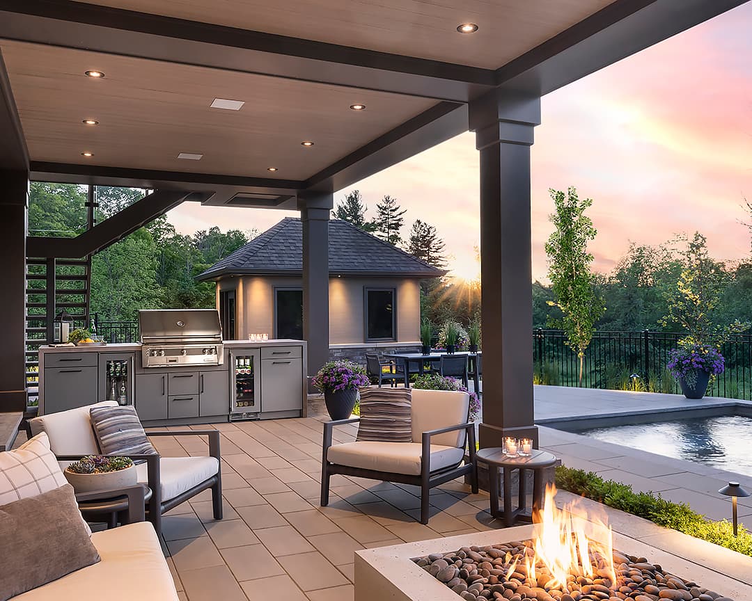 outdoor kitchen including grill, bar fridge, fire pit, pool in a backyard north of Toronto near sunset