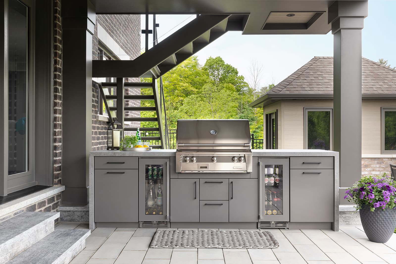 woman leaning on outdoor kitchen cabinet by pool in backyard