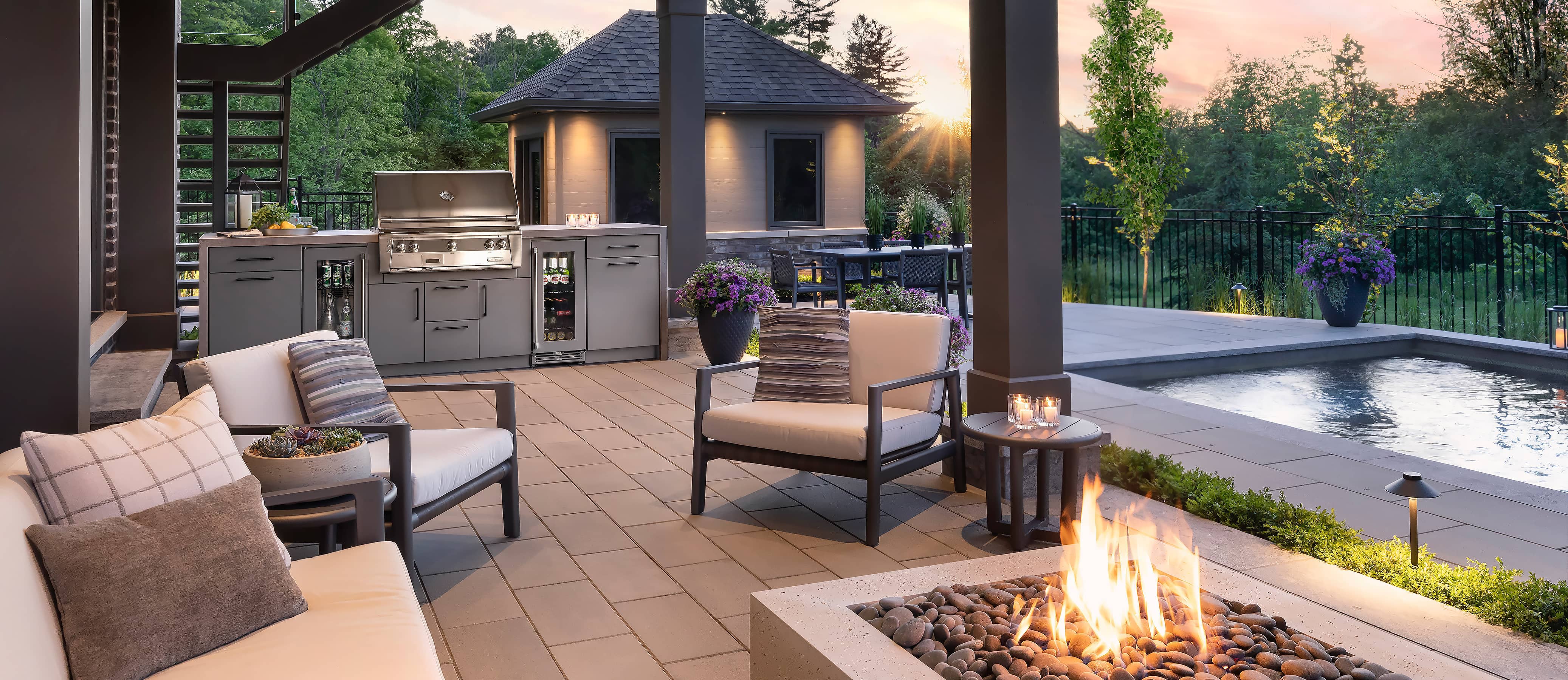 outdoor kitchen including grill, bar fridge, fire pit, pool in a backyard north of Toronto near sunset