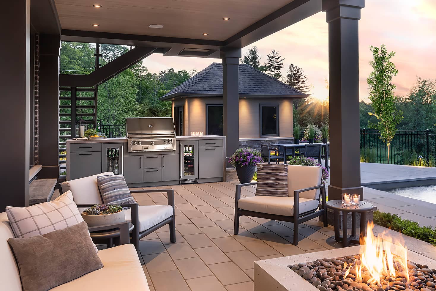 outdoor kitchen including grill, bar fridge, fire pit, pool in a backyard north of Toronto near sunset