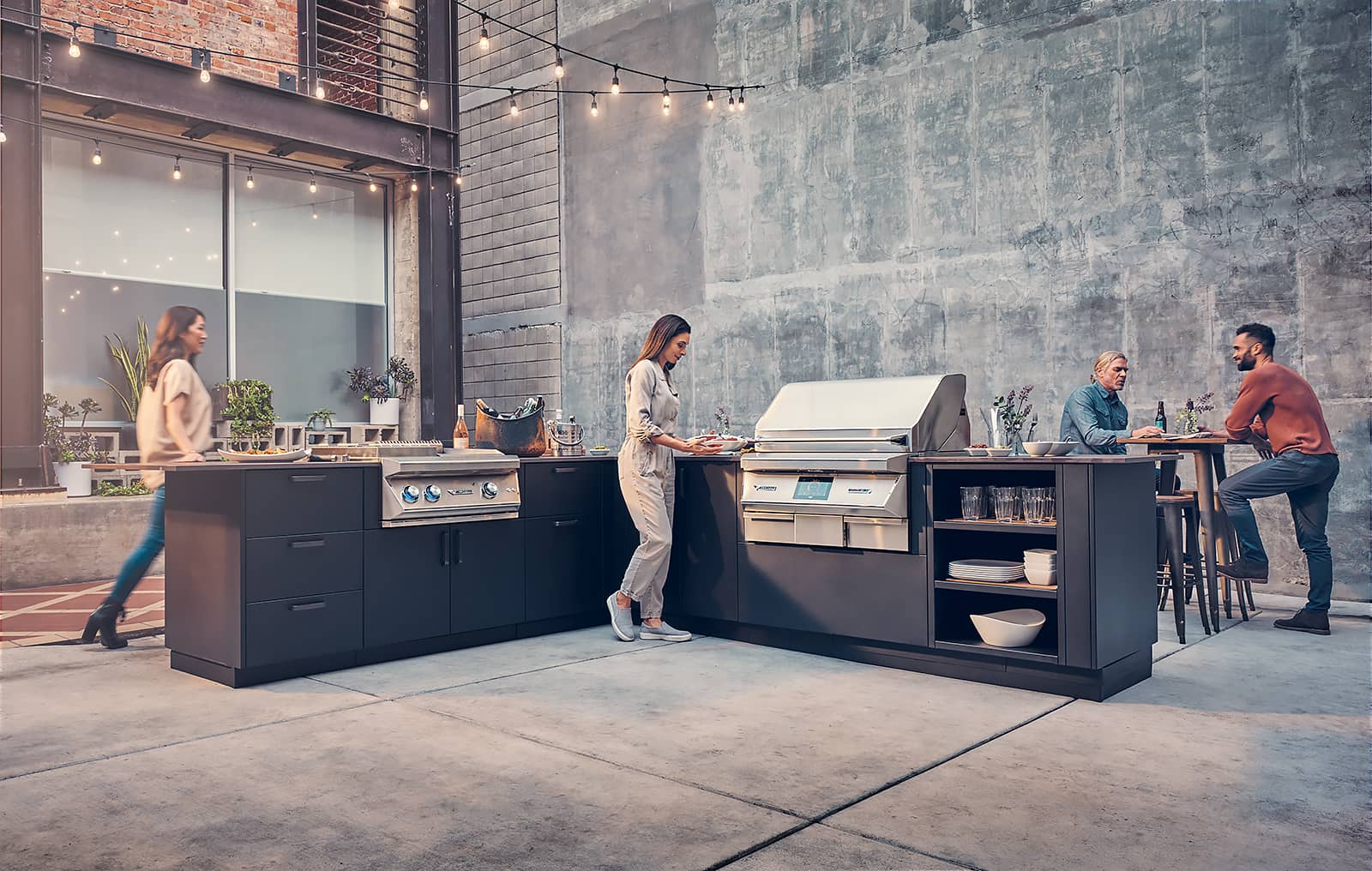 4 people in an outdoor courtyard around pellet grill